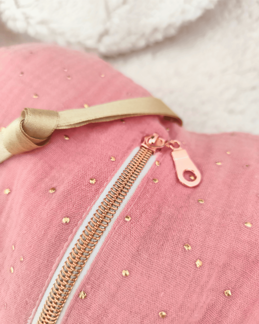 Gros plan sur la fermeture éclair rose gold d’une veilleuse cœur en tissu double gaze rose