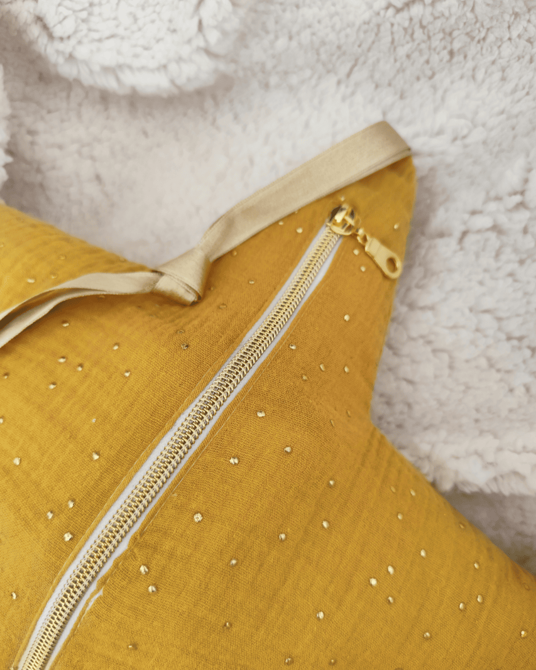 ros plan sur la fermeture éclair dorée d'une veilleuse étoile en tissu double gaze moutarde, détail du ruban de suspension